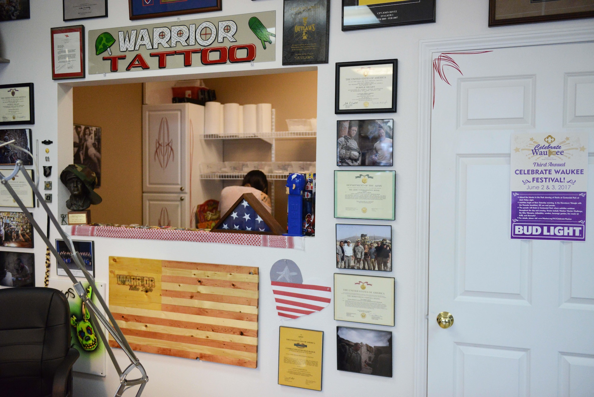 The back wall of Warrior Tattoo Studio displays awards and photos at Warrior Tattoo Studio in Waukee, Iowa. John Hintz, owner and artist, named the studio to honor those he served with. (U.S. Air National Guard photo by Airman 1st Class Katelyn Sprott)