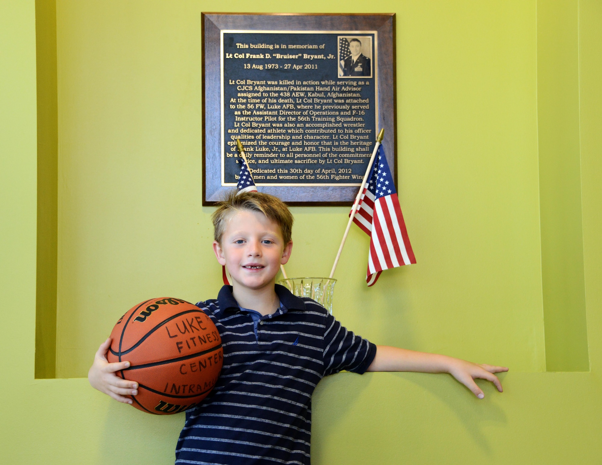 7-year-old Sean Luke, son of Frank Bryant Jr., poses for a picture in front of his father’s memorial plaque during Bryant Fitness Center’s Grand Opening Ceremony June 27, 2017, at Luke Air Force Base, Ariz. Sean was just one year old when his father was killed in action while serving in Afghanistan. (U.S. Air Force photo by Airman 1st Class Alexander Cook)   