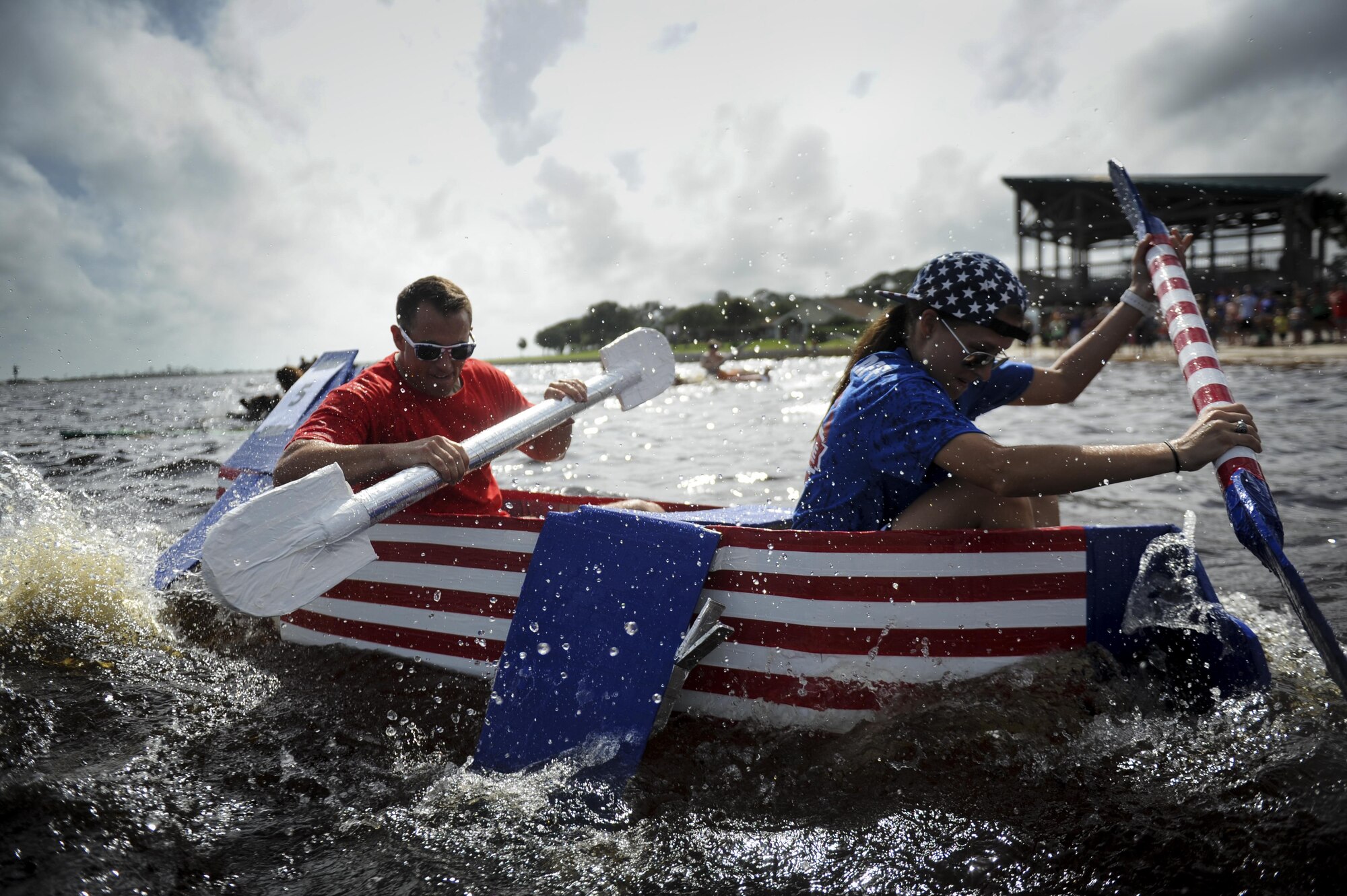 Capt. Conor Mulligan, left, the military personnel flight commander with the 1st Special Operations Force Support Squadron, and 2nd Lt. Taylor Pearson, a force support officer deputy with the 1st SOFSS, paddle to the finish line during the cardboard boat regatta at Hurlburt Field, Fla., June 24, 2017. Mulligan and Pearson won first place out of six other teams that competed in the race. (U.S. Air Force photo by Airman 1st Class Dennis Spain)