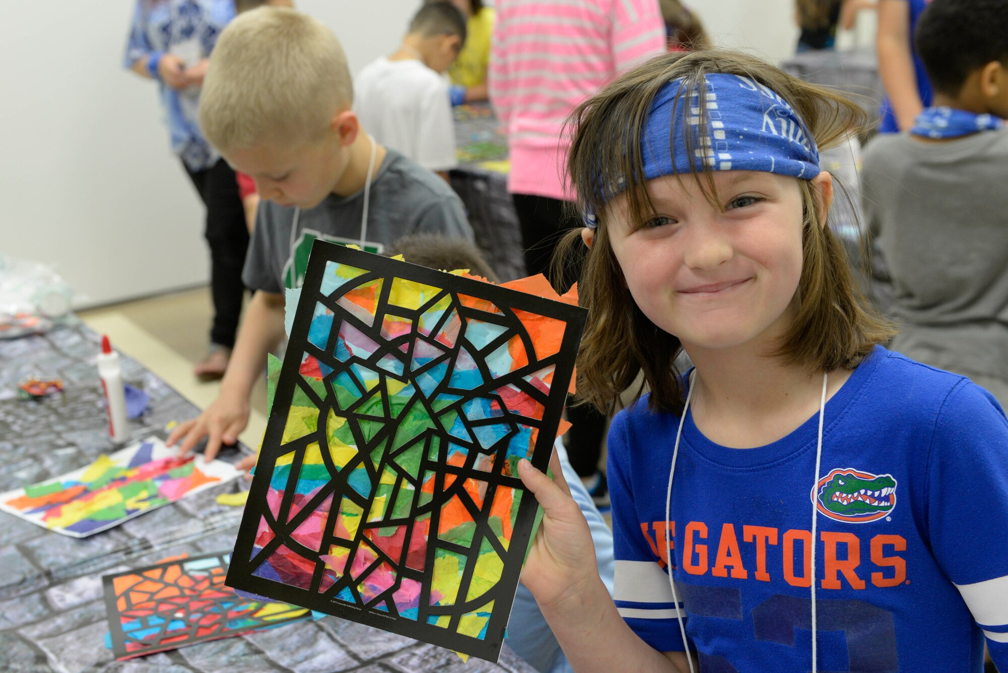 A child poses with her stained glass window artwork at Yokota Air Base, Japan, June 23, 2017. A different story from the Bible served as the theme for the activities each day.