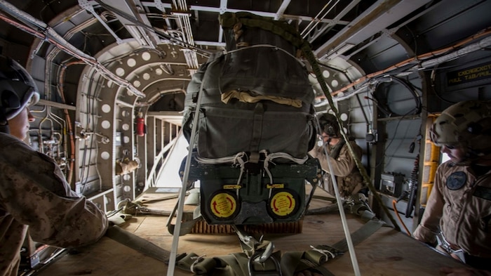 Marine parachute riggers with 1st Marine Logistics Group and a crew chief with Marine Operational Test and Evaluation Squadron-22 (VMX-22) prepare to deploy a palletized load from above 10,000 feet during the Joint Precision Airdrop System testing Aug. 1, at the U.S. Army Yuma Proving Ground. The JPADS systems use GPS, a modular autonomous guidance unit, or MAGU, a parachute and electric motors to guide cargo within 150 meters of their target points. Marine Corps Systems Command fielded the last of 162 JPADS to the fleet in April, turning the page from acquisition to sustainment of the system for the Corps. (U.S. Marine Corps photo by Cpl. Reba James)