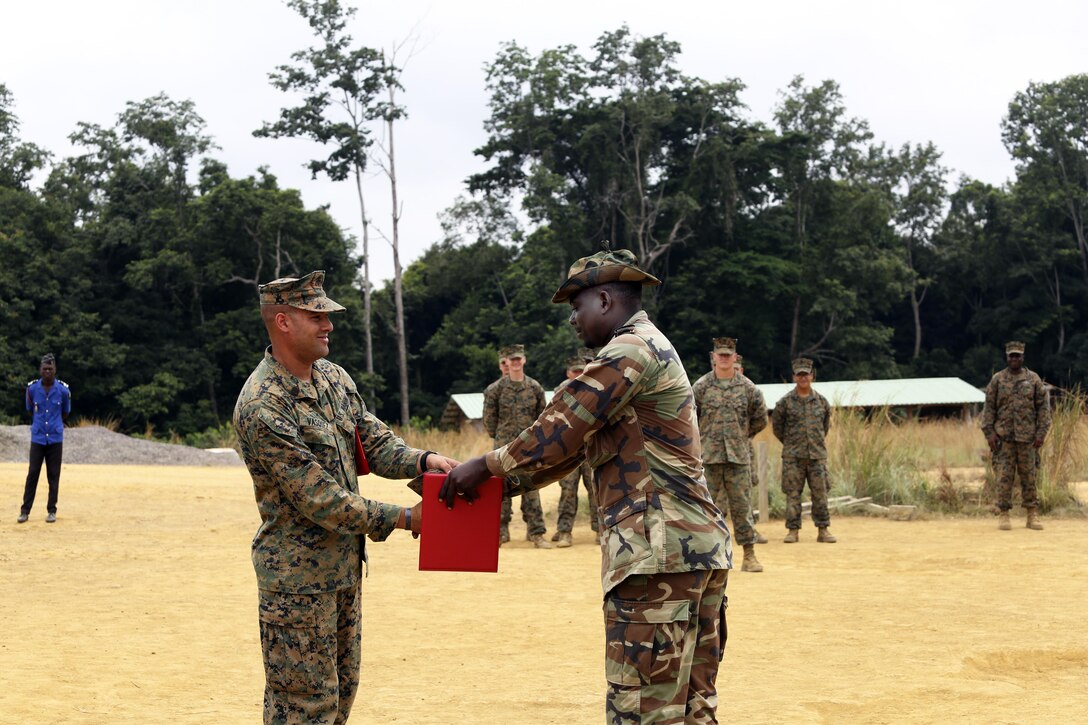 Marine Corps Gunnery Sgt. Juan Vasquez, assigned to Special Purpose Marine Air-Ground Task Force Crisis Response-Africa, presents a certificate of completion to a Gabonese soldier who was also the honor graduate during training at Camp Mokekou, Gabon, June 15, 2016. The collaborative 5-week course, led by a team of Marines assigned to Special Purpose Marine Air Ground Task Force-Crisis Response-Africa, consisted of train-the-trainer style cadre development courses intended to empower leadership and enhance skills necessary to interdict illicit trafficking. Marine Corps photo by 1st Lt. Johnny Henderson