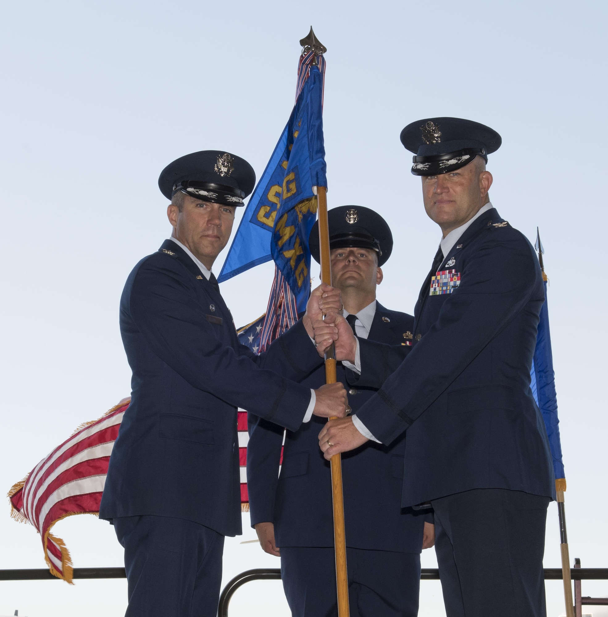 U.S. Air Force Col. John Klein, commander, 60th Air Mobility Wing, Travis AFB, Calif., passes the 60th Maintenance Group guidon to Col. David Hammerschmidt, incoming 60th MXG commander, during a Change of Command Ceremony where Col. Earl Scott relinquished command to Hammerschmidt, June 23, 2017. The 60th Maintenance Group has 2,200 active, civilian, and reserve personnel supporting organizational and field-level maintenance for 18 C-5M Super Galaxy, 13 C-17 Globemaster, and 27 KC-10 Extender aircraft at Air Mobility Command's largest wing. U.S. Air Force Col. Earl S. Scott relinquished command to Col. David A. Hammerschmidt during a ceremony rooted in military history dating back to the 18th Century where the command flag is passed to the individual assuming command in the presence of the entire unit. (U.S. Air Force photo/ Heide Couch)