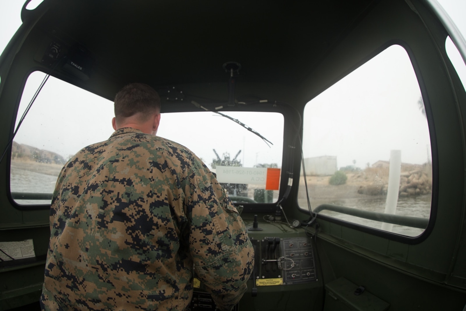 U.S. Marine Cpl. Braxton Shrader, a combat engineer with Bridge Company, 7th Engineer Support Battalion, 1st Marine Logistics Group observes his surroundings while on the Bridge Erection Boat (BEB) during a boat licensing course along the coast of Camp Pendleton, Calif., June 21, 2017 The BEB deploys improved ribbon bridges, which are long two-way platforms used to transport heavy equipment, such as tanks, over bodies of water.  (U.S. Marine Corps photo by Lance Cpl. Timothy Shoemaker)