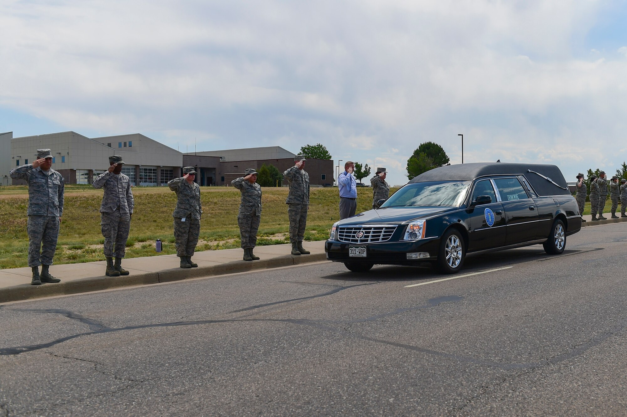 Members of Team Buckley render a final salute to Major Elgin Ross, Chief, Total Force Service Center, assigned to Headquarters Air Reserve Personnel Center, June 27, 2017, on Buckley Air Force Base, Colo. Ross tragically passed away after becoming unresponsive while conducting his physical training test on June 16. The Buckley community paid their last respects to Ross and his family at a funeral procession on Aspen Street, from the Mississippi Gate to the 6th Avenue Gate. (U.S. Air Force photo by Airman Jacob Deatherage/Released)