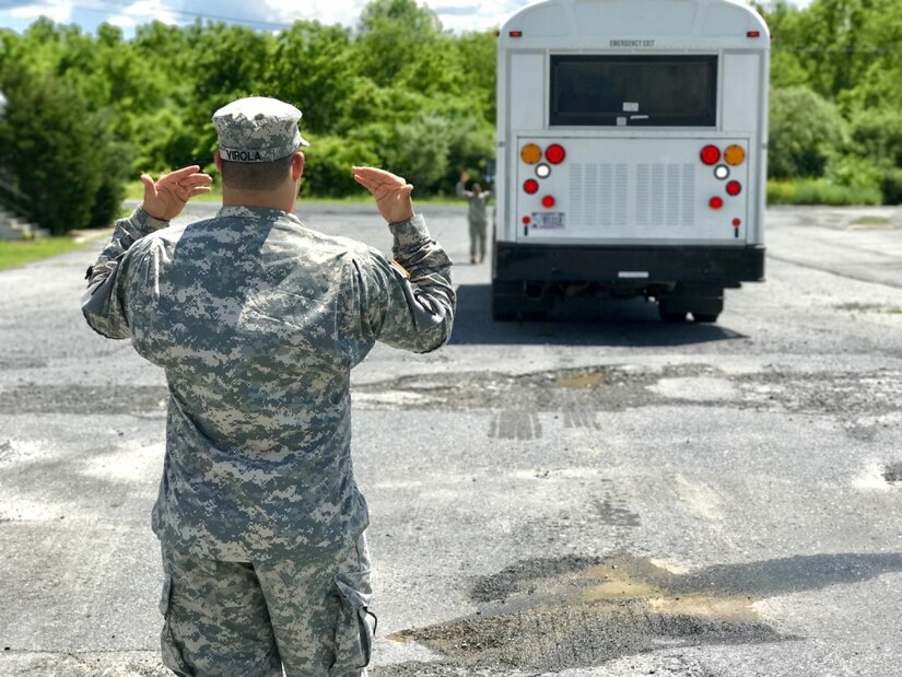 Pennsylvania Army National Guard Spc. Luis Virola, a light wheeled vehicle mechanic with Headquarters and Headquarters Detachment, 213th Regional Support Group, ground-guides a classmate during bus driver training at Fort Indiantown Gap, Pa., June 9, 2017. Army photo by Army Pvt. Daniel Olson