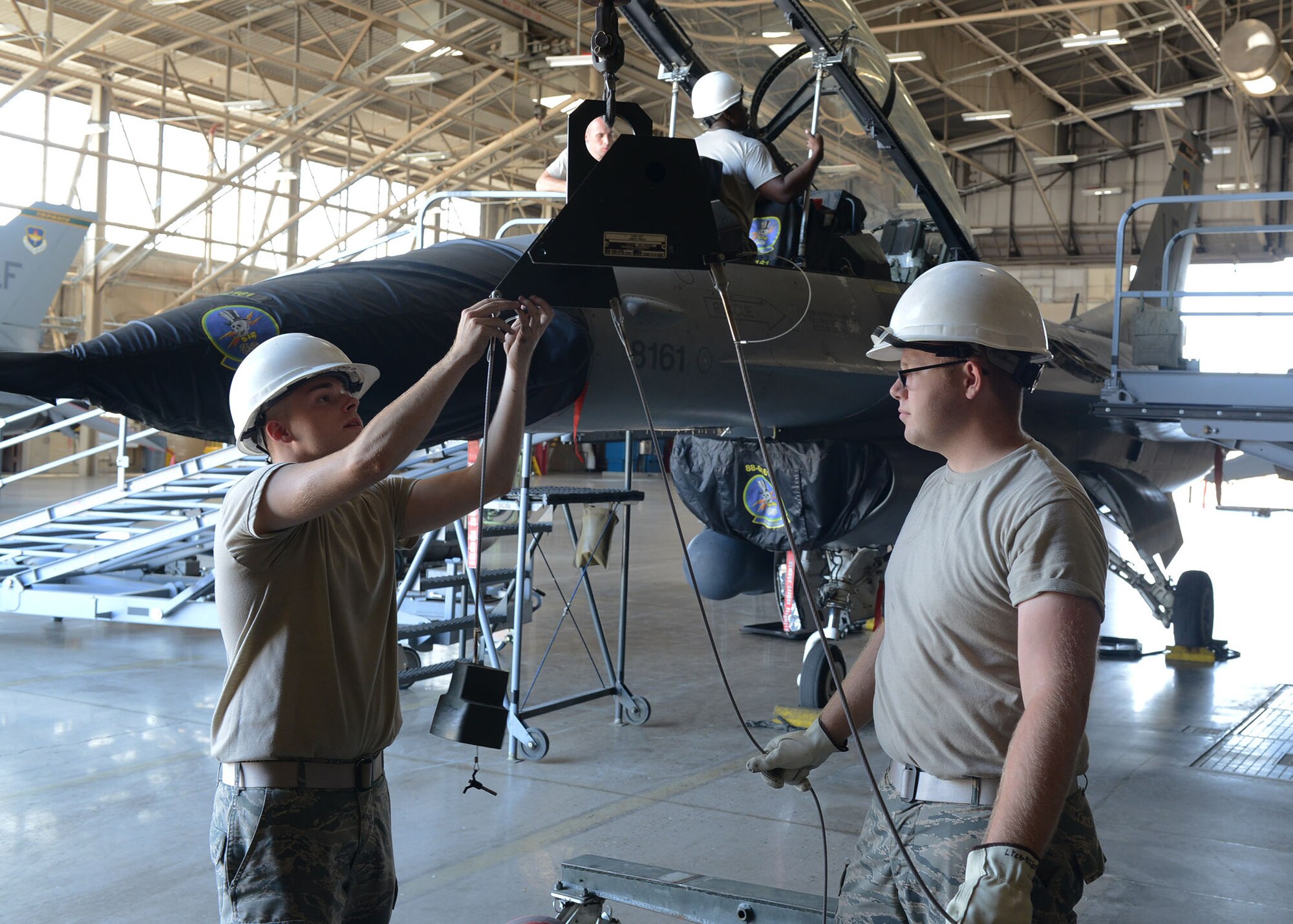 56th Component Maintenance Squadron Egress Airmen prepare a crane to remove a canopy and seat from an F-16 Fighting Falcon June 26, 2017, at Luke Air Force Base, Ariz. Aircrew egress technicians perform maintenance on warning lights, emergency oxygen systems, canopies, lap belts and shoulder harnesses. (U.S. Air Force photo by Senior Airman James Hensley)