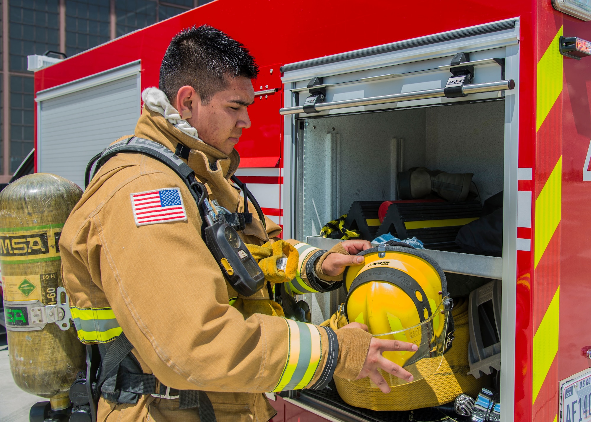 Airman 1st Class Macario Martinez, 375th CES fire fighter, grabs his helmet to participate in a training exercise at Scott Air Force Base, Ill. on June 22, 2017. The exercise was part of the unit's Airport Rescue and Fire Fighting's training which tests their ability to arrive on scene, fight fires, and provide a rescue path as well as recover or rescue personnel. (U.S. Air Force photo by Airman 1st Class Daniel Garcia)
