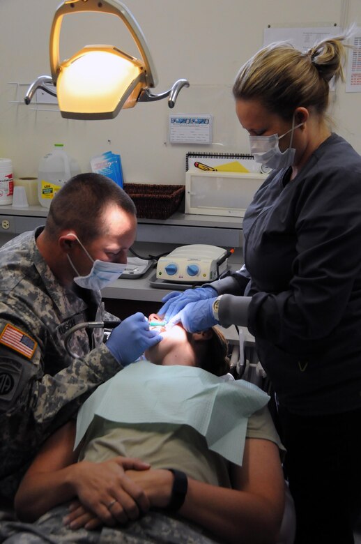 Sgt. Matthew Kunsch, a dental specialist assigned to 7406th Troop Medical Clinic located in Kansas City, Missouri, learns how to perform a general cleaning on fellow Soldier, Sgt. Jennifer Kunsch, from staff member Michelle Scott, a dental hygienist on the team.  Both Matthew and Jennifer are  part of a small medical team of approximately 25 U.S. Army Reserve Soldiers who are working in partnership with Rosebud Indian Health Service to provide medical care to the local tribal population. 
