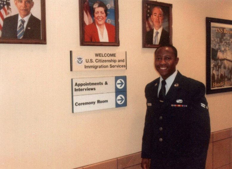 Then U.S. Air Force Airman 1st Class Tinashe Machona, assigned to the  116th Air Control Wing, poses for a photograph in the foyer a United States Citizenship and Immigration building, during a citizenship ceremony, in Atlanta, Ga., Jan. 12, 2012. Machona expedited his U.S. Citizenship after joining the U.S. Military. (Courtesy photo, 2nd Lt. Tinashe Machona)