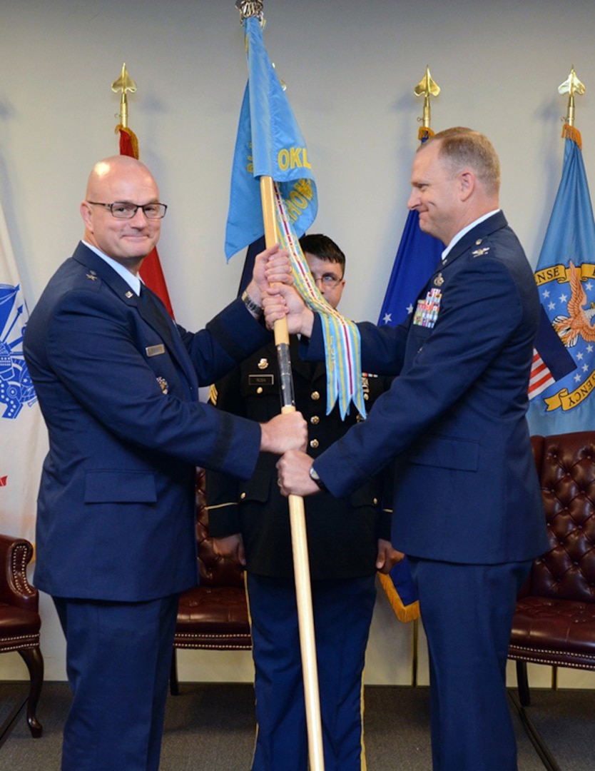 Air Force Col. Kenton Ruthardt, right, relinquishes command of Defense Logistics Agency at Oklahoma City to Air Force Lt. Col. James Malec. Former DLA Aviation Commander Air Force Brig. Gen. Allan Day, left, officiated the ceremony held at the Tinker Aerospace Complex, Tinker Air Force Base, Oklahoma, June 23, 2017.
