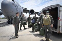 Pilots from the foreign exchange program and aircrew from the 14th Airlift Squadron, grab their flight equipment and prepare to load onto a C-17 Globemaster III aircraft here, June 26, 2017. The program strives to promote mutual understanding and trust, enhance interoperability, strengthen air force to air force ties and develop long-term professional and personal relationships.