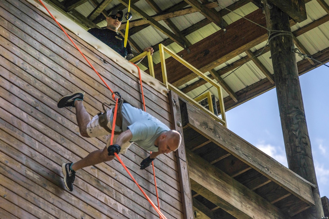 A soldier demonstrates how to rappel down a 40-foot tower at Camp Dawson, W.V., June 26, 2017, during a camp aimed at teaching children of service members about their parents’ experiences while deployed. The soldier is assigned to the West Virginia Army National Guard’s civil support team. Army photo by Sgt. Lisa M. Sadler