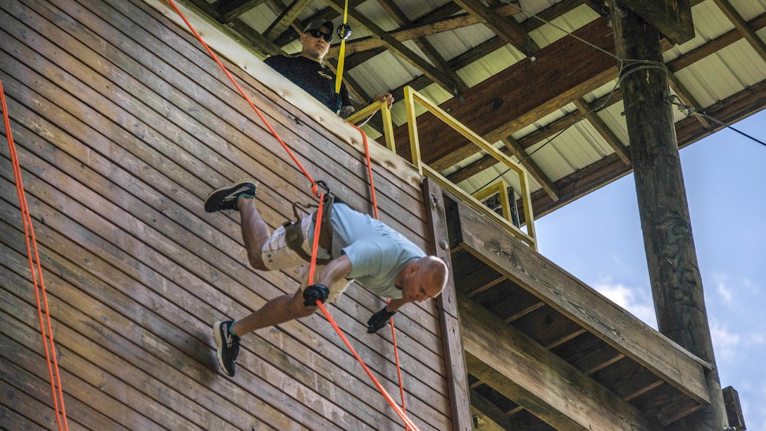 A soldier demonstrates how to rappel down a 40-foot tower at Camp Dawson, W.V., June 26, 2017, during a camp aimed at teaching children of service members about their parents’ experiences while deployed. The soldier is assigned to the West Virginia Army National Guard’s civil support team. Army photo by Sgt. Lisa M. Sadler