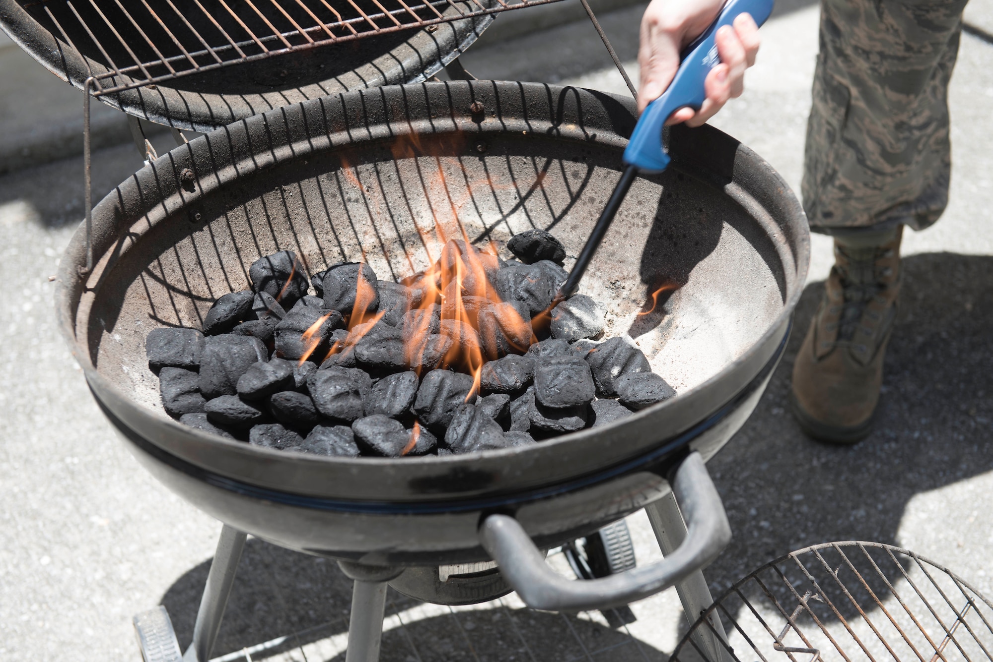 A U.S. Airman lights a barbeque June 28, 2017, at Kadena Air Base, Japan. During the summer, many individuals will barbecue and enjoy the outdoors. Maintaining safe fire handling practices can ensure fewer house fires occur. (U.S Air Force photo by Senior Airman Quay Drawdy)