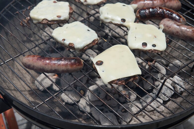 Burgers and hotdogs cook on a grill June 28, 2017, at Kadena Air Base, Japan. Grease from grilling can cause fires to flare out of control. Proper situational awareness and maintaining fire extinguishers can reduce the likelihood of fires spreading onto other property and homes. (U.S Air Force photo by Senior Airman Quay Drawdy)