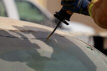 An Airman with the 380th Expeditionary Civil Engineer Squadron Fire Department cuts out a vehicle's windshield prior to training June 23, 2017, at an undisclosed location in southwest Asia. Windshields and other glass were removed prior to vehicle extrication training for safety. (U.S. Air Force photo by Senior Airman Preston Webb)