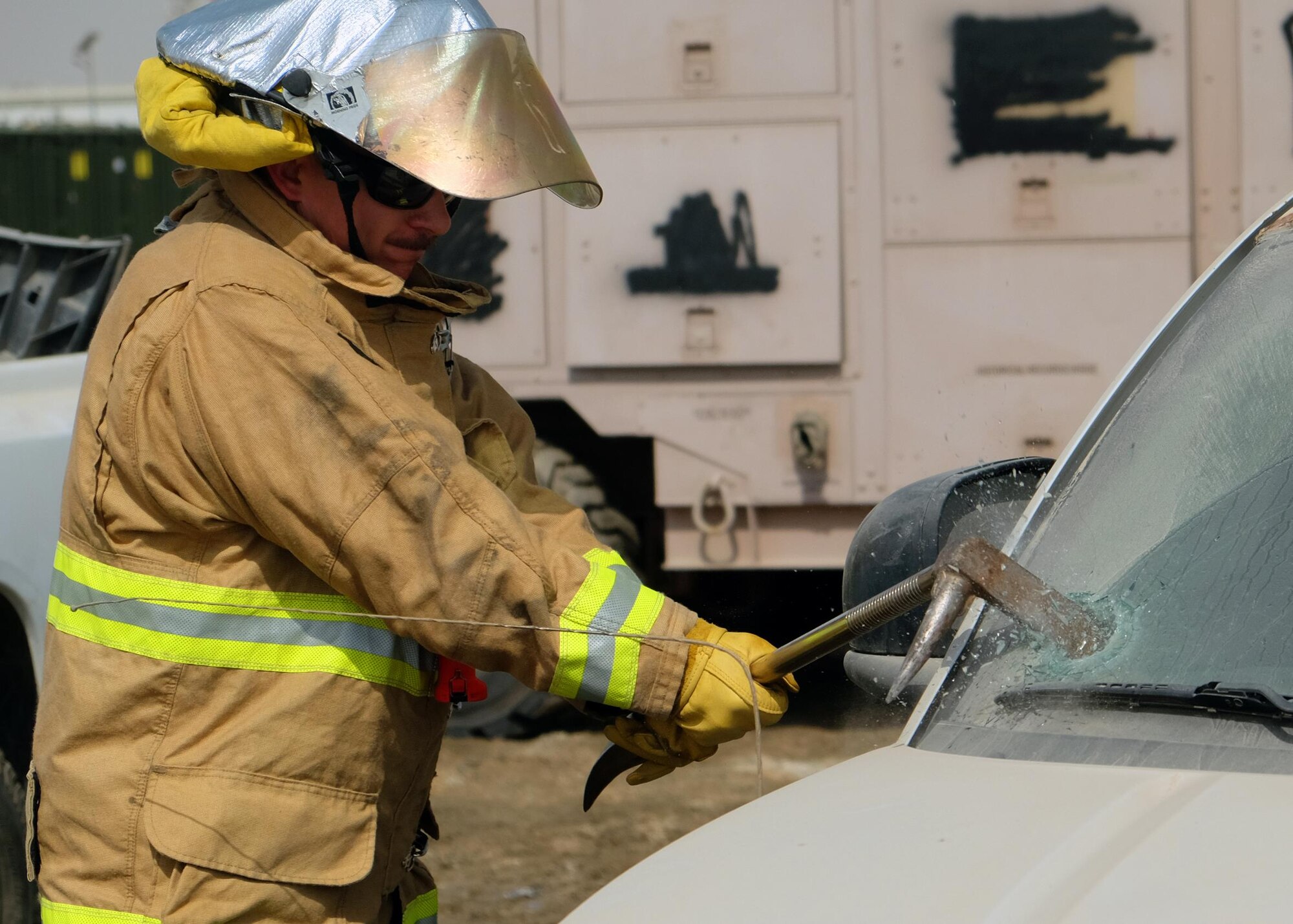 Master Sgt. Anthony, 380th Expeditionary Civil Engineer Squadron Fire Department NCO in charge of training, punctures a windshield June 23, 2017, at an undisclosed location in southwest Asia. Windshields and other glass were removed prior to vehicle extrication training for safety. (U.S. Air Force photo by Senior Airman Preston Webb)