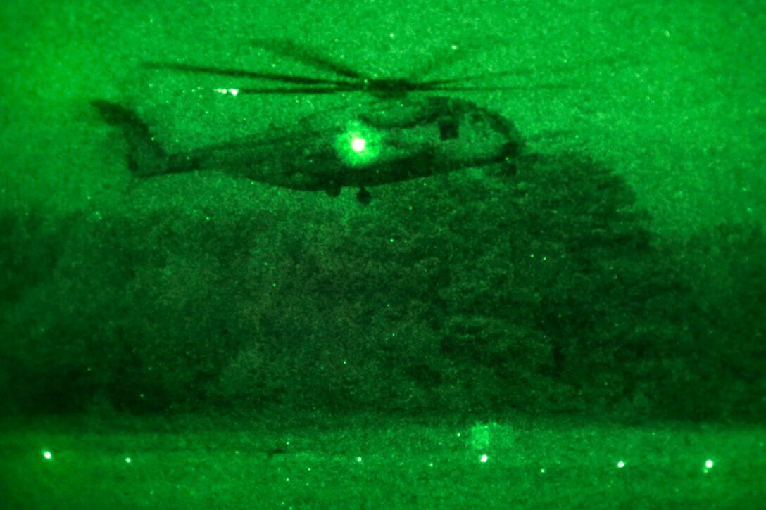 As seen through a night vision device, a CH-53 Super Stallion helicopter prepares to land during helicopter support team training on landing zone Albatross at Camp Lejeune, N.C., June 27, 2017. The Marines are assigned to 2nd Transportation Support Battalion. Marine Corps photo by Lance Cpl. Tyler W. Stewart