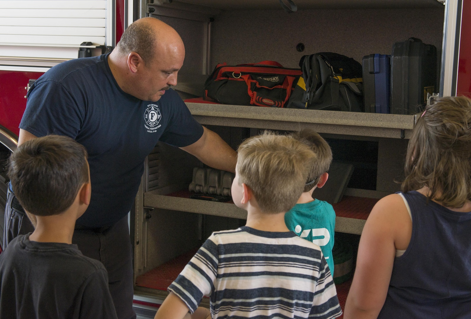 Avery Carter, 502nd Civil Engineering Squadron firefighter, shows children from Vibrant ABA Solutions the various kinds of equipment they use when there is an emergency during a open house tour of Fire Station 2 June 23, 2017, at Joint Base San Antonio-Lackland, Texas. (U.S. Air Force photo by Senior Airman Krystal Wright)