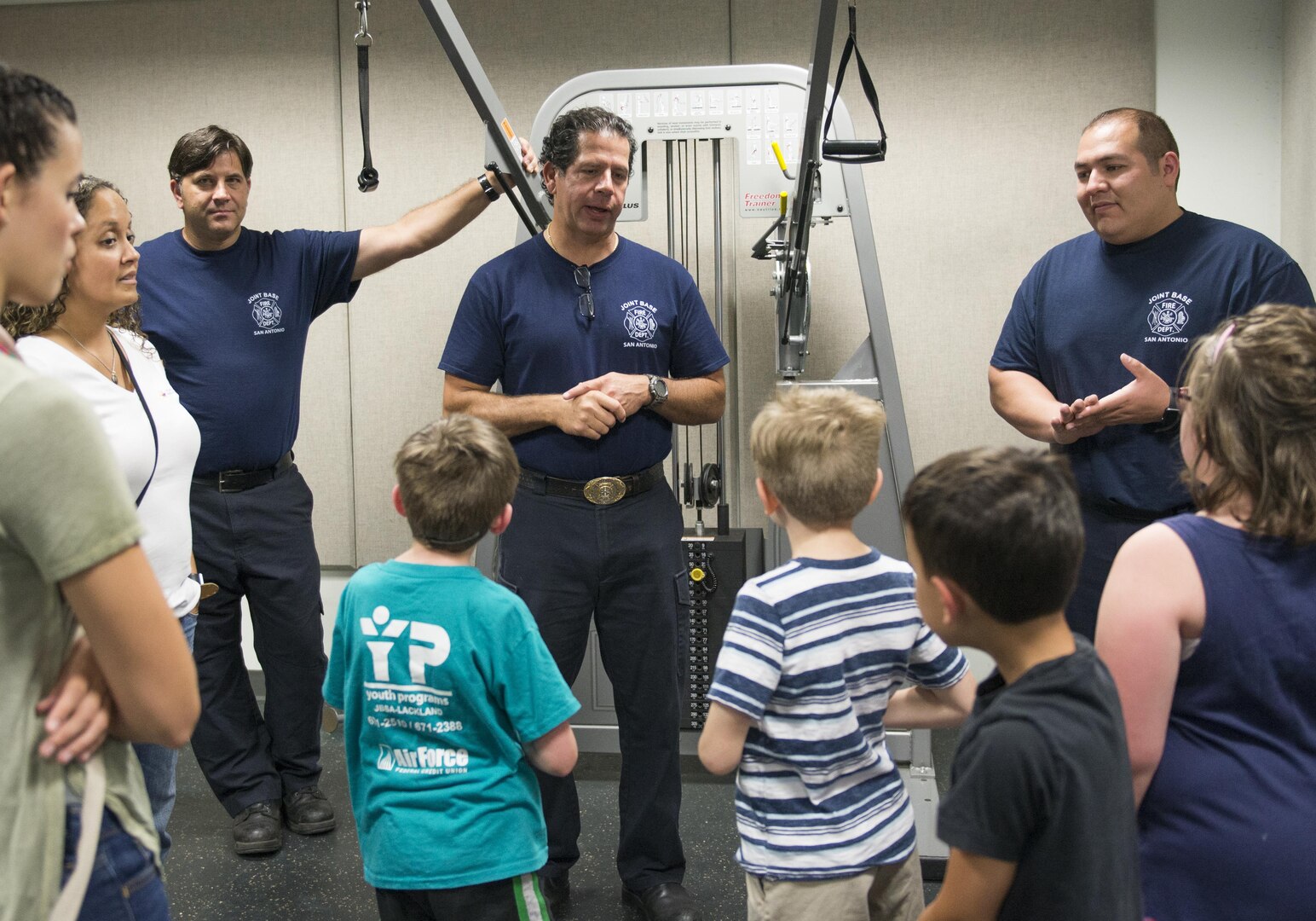 (From the left) Thomas Russ, Michael Martinez, and Jeffery Pardo, 502nd Civil Engineering Squadron firefighters, shows children from Vibrant ABA Solutions their workout room during a open house tour of Fire Station 2 June 23, 2017, at Joint Base San Antonio-Lackland, Texas. One of the goals of hosting tour is to make children more comfortable with firefighters so they won’t be frightened during an emergency. (U.S. Air Force photo by Senior Airman Krystal Wright)