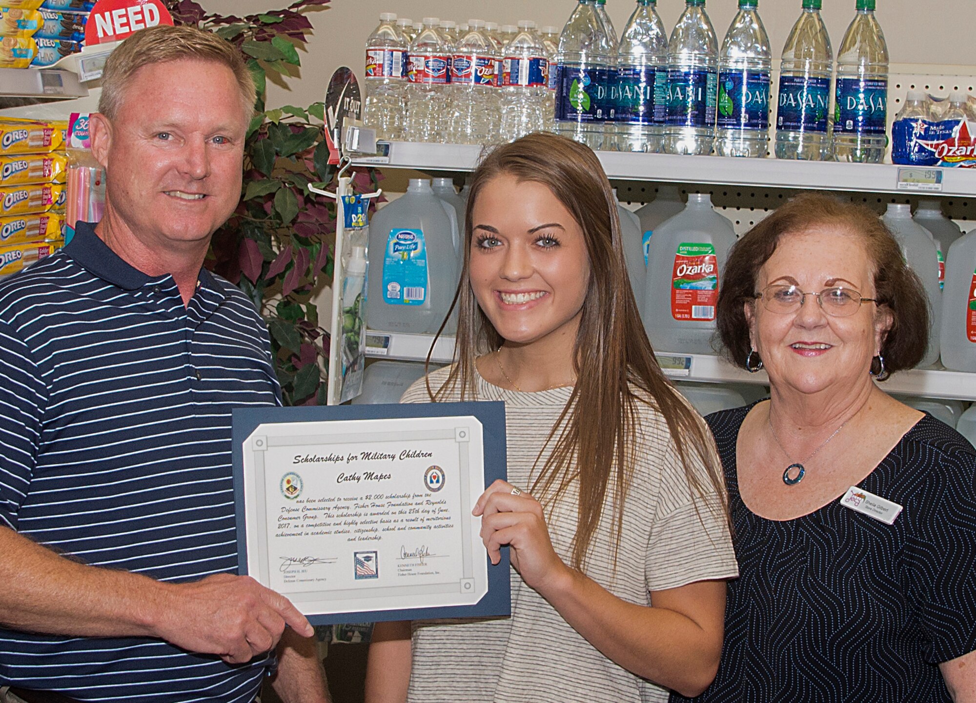 Paul Weber, left, and Sheila Gilbert, right, present a $2,000 scholarship to Cathy Mapes at the Vance Commissary June 28. Weber represented the scholarship sponsor Reynolds Consumer Produce and OSC/Webco, and Gilbert is the director of the Commissary. Cathy plans to attend Oklahoma State University in Stillwater, and pursue a degree in Animal Science. (U.S. Air Force photo/ Airman 1st Class Taylor Crul)