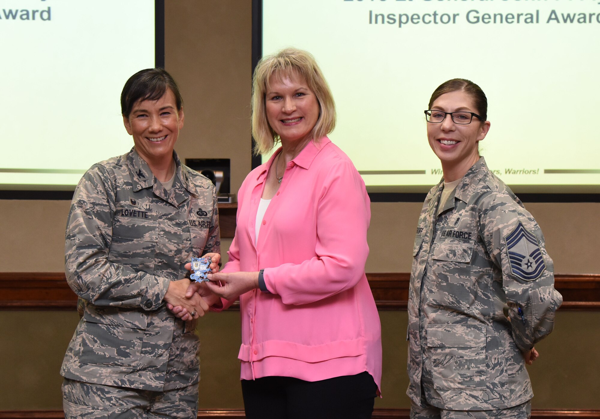 Col. Debra Lovette, 81st Training Wing commander, and Chief Master Sgt. Julie Bottroff, 81st Medical Group superintendent, present Stephanie Goff, 81st TRW complaints resolution director, a coin during a wing staff meeting at Stennis Hall June 28, 2017, on Keesler Air Force Base, Miss. Lovette recognized Goff for being instrumental in the inspector general team earning the 2016 Lt. Gen. John P. Flynn Inspector General Award for the best complaints resolutions program office in the Air Force. (U.S. Air Force photo by Kemberly Groue)