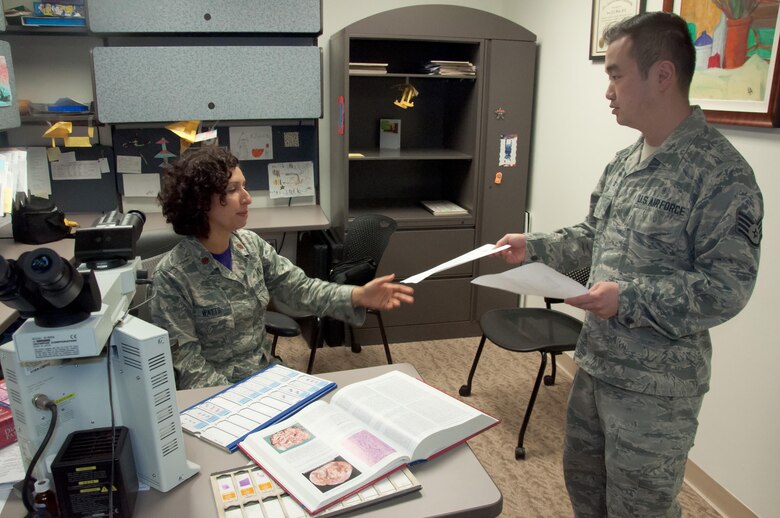 Staff Sgt. Steven Lam, Wright-Patterson Medical Center histology technician, provides Maj. (Dr.) Luisa Watts, staff pathologist, additional information for a pending case. Watts, along with three other staff pathologists at the WPMC, use information doctors provide, along with reviews of biological materials and reference materials, in forming their diagnoses. (U.S. Air Force photo/John Harrington)