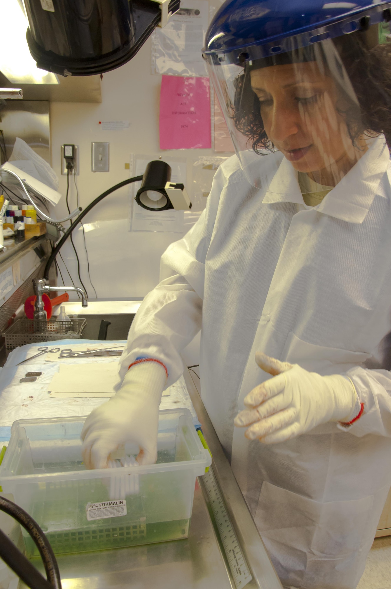 Maj. (Dr.) Luisa Watts, Wright-Patterson Medical Center staff pathologist, submerges biological samples of interest, gathered in a pathological grossing, into a container of the preservative formalin in advance of preparing them for processing by histology technicians. The material will be placed onto glass slides for microscopic examination. Watts, along with three other staff pathologists at the WPMC, use information doctors provide, along with reviews of biological materials and reference materials, in forming their diagnoses. (U.S. Air Force photo/John Harrington) 
