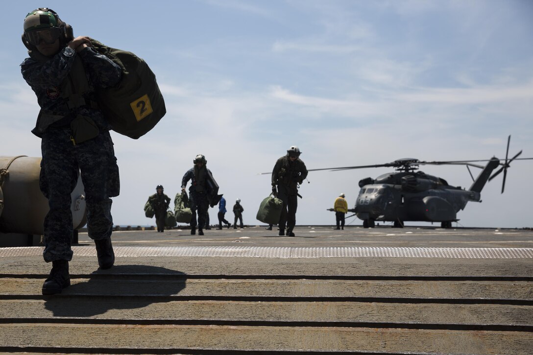 Sailors debark an MH-53 helicopter and unload gear aboard the USS Whidbey Island (LDS-41), June 13, 2017. Military personel all across the department of defense are making preparations for Sail Boston 2017 to showcase their vast cabailities to the public. The sailors boarded the ship to display an MH-53 helicopter during the festivities. The sailors are assigned to HM15. (U.S. Marine Corps photo by Lance Cpl. Jailine L. Martinez)