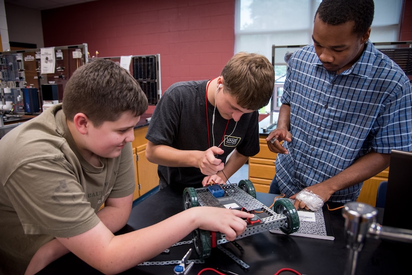 Space and Naval Warfare Systems Center (SSC) Atlantic intern Tyler Taylor assists students building a VEX robot during the fifth annual SSC Atlantic-hosted Cyber Security Summer Camp at Burke High School June 19-23. More than 30 SSC Atlantic employees volunteered along with others from Trident Technical College, teaching more than 135 students from Charleston, Berkeley and Dorchester county school districts.