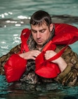 Staff Sgt. Daniel Vehslage, 54th Helicopter Squadron special missions aviator, secures a flotation device during underwater egress survival training at Minot Air Force Base, N.D., June 22, 2017. During the training, the 54th HS Airmen learned how to escape a simulated helicopter crash and properly use common rescue devices. (U.S. Air Force photo by Airman 1st Class Jonathan McElderry)
