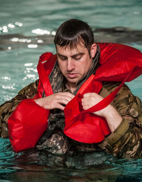 Staff Sgt. Daniel Vehslage, 54th Helicopter Squadron special missions aviator, secures a flotation device during underwater egress survival training at Minot Air Force Base, N.D., June 22, 2017. During the training, the 54th HS Airmen learned how to escape a simulated helicopter crash and properly use common rescue devices. (U.S. Air Force photo by Airman 1st Class Jonathan McElderry)