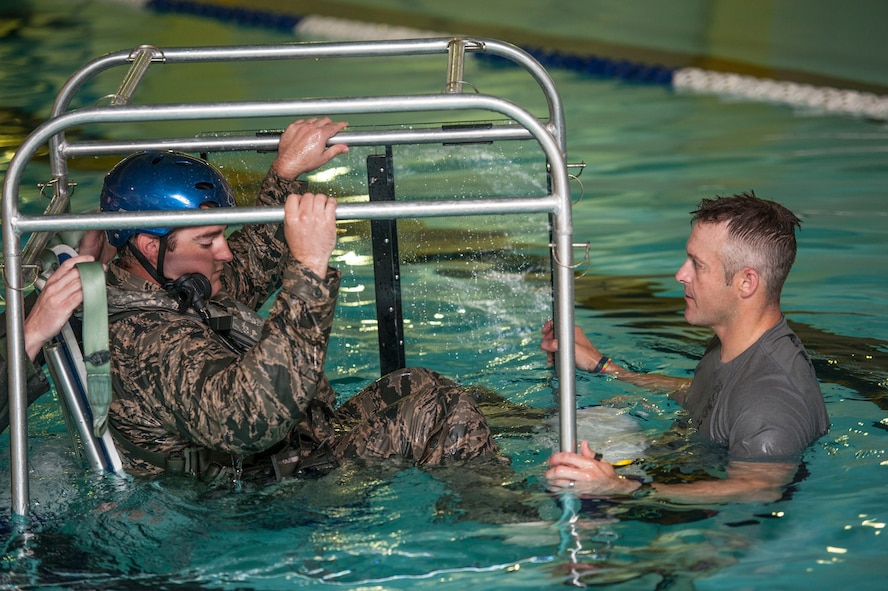 (From left) Capt. David Shadoin, 54th Helicopter Squadron pilot, is briefed by Tech. Sgt. Clifton Cleveland, 5th Operations Support Squadron survival, evasion, resistance and escape specialist, during underwater survival training at Minot Air Force Base, N.D., June 22, 2017. The shallow water egress trainer allows Airmen to practice escape procedures during a simulated helicopter crash. (U.S. Air Force photo by Airman 1st Class Jonathan McElderry)