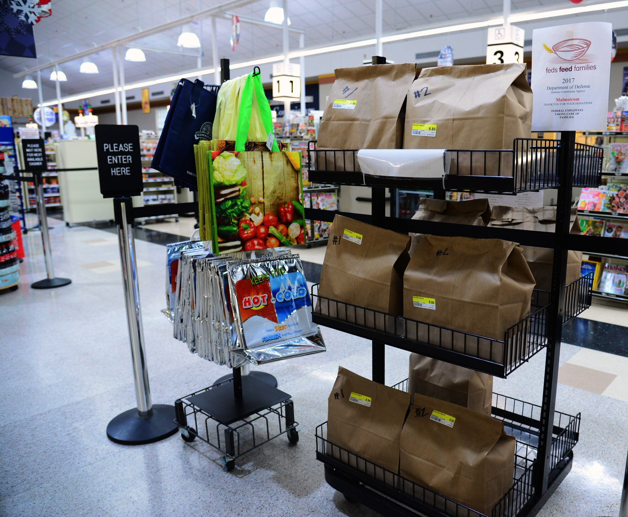 A stand of premade Feds Feed Families donation bags are displayed June 29, 2017, at Malmstrom Air Force Base, Mont. The Malmstrom Commissary curated bags for convenient donation; one for food items and one for non-food items, such as toiletries. (U.S. Air Force photo/Senior Airman Magen M. Reeves)  