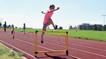 Brooke Sense, Summer Enrichment Program participant, jumps over hurdles at Schriever Air Force Base, Colorado, Monday, June 26, 2017. The Schriever School Age Care program invited Ellicott summer camp participants to the installation for several activities as a part of the three-day program.  (U.S. Air Force photo/Senior Airman Arielle Vasquez)