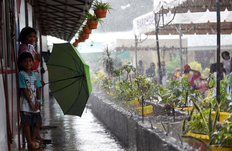 A woman and child from Bogo City wait for rain to stop at a Pacific Angel 2017 health services site in Northern Cebu Province, Philippines, June 26, 2017. PACANGEL participants from six different nations work together with local nongovernmental organizations to administer medical care, including general health, optometry, dental, physical therapy and pediatrics, to the people of Northern Cebu Province. (U.S. Air Force photo by Tech. Sgt. Jeff Andrejcik)