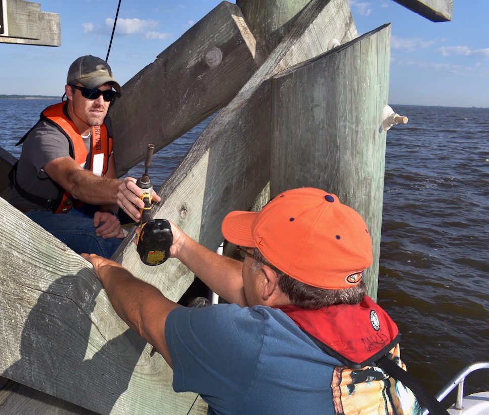Glenn Duval, water management program, passes a drill to Richard Allen, coastal engineer, so that he can secure newly installed gauges on the U.S. Coast Guard navigation range in Mobile Bay. Field data collection completed for the Mobile Harbor GRR includes wetland delineation, seagrass surveys, bottom-dwelling organisms, fisheries and oysters.
