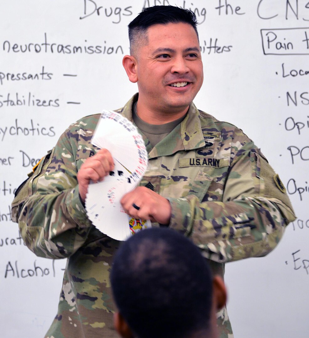 Staff Sgt. John Blaz, Interservice Respiratory Therapy Program instructor at the Medical Education and Training Campus, Joint Base San Antonio-Fort Sam Houston, shows a deck of cards during a magic trick he performs for his students at the beginning of a recent class.