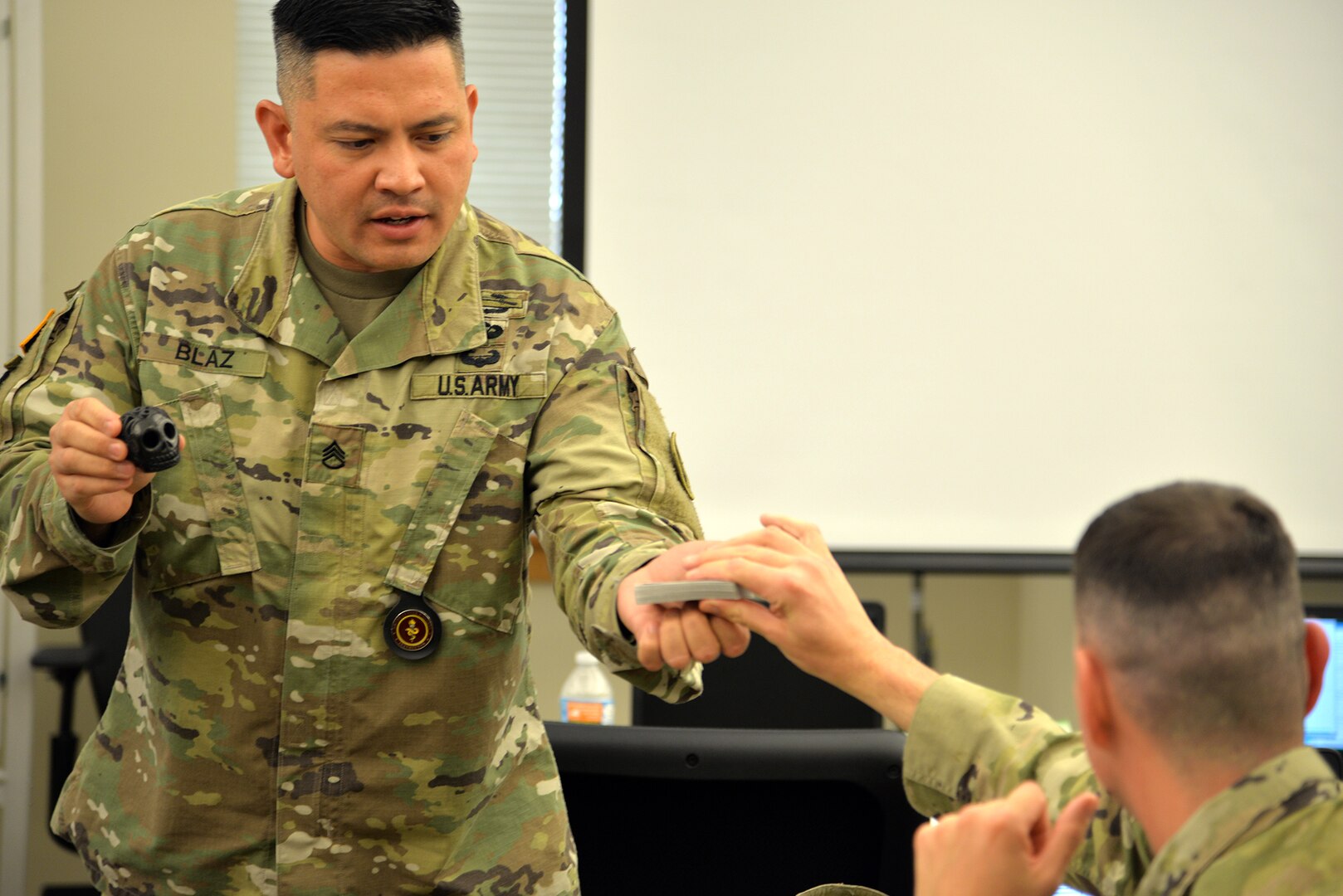 Staff Sgt. John Blaz (left), Interservice Respiratory Therapy Program instructor at the Medical Education and Training Campus, Joint Base San Antonio-Fort Sam Houston, asks Sgt. Dave Allen, Interservice Respiratory Therapy student, to pick from a deck of cards during a magic trick Blaz performed for his students in class.