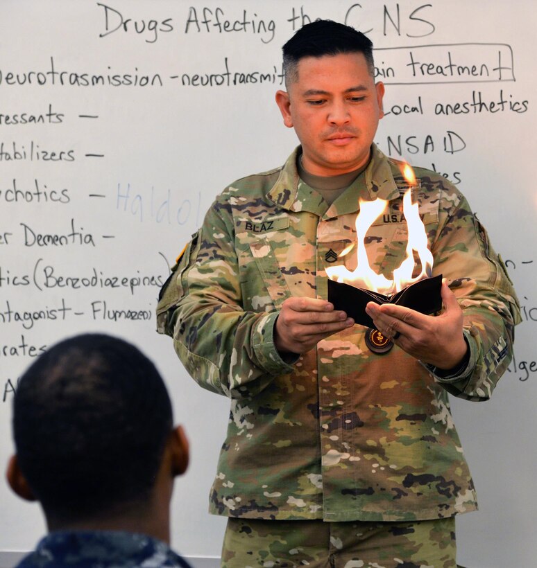 Staff Sgt. John Blaz, Interservice Respiratory Therapy Program instructor at the Medical Education and Training Campus, Joint Base San Antonio-Fort Sam Houston, performs a magic trick for his students in which he lights a piece of paper that turns into money during class.
