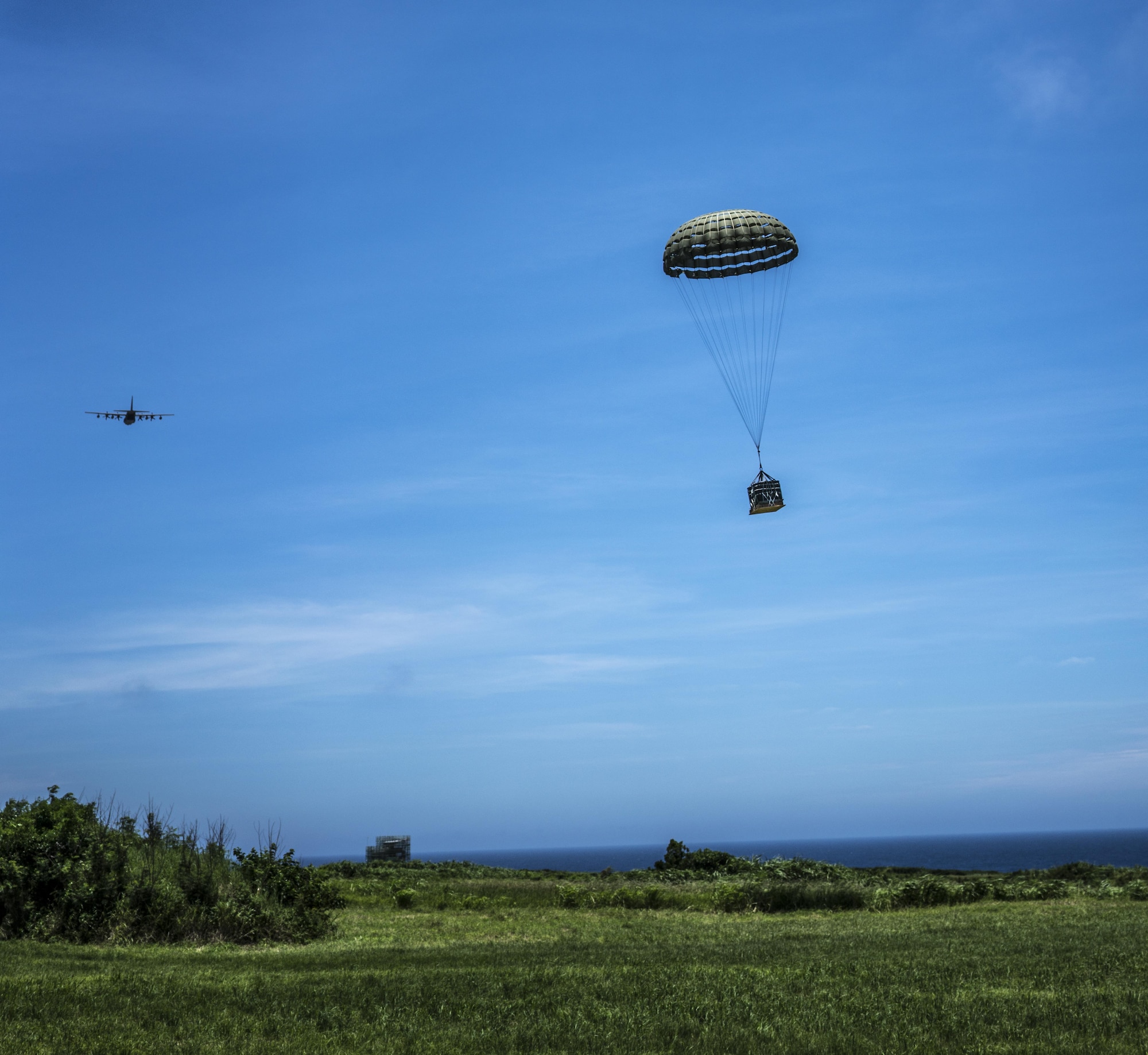 A U.S. Air Force MC-130J Commando II drops a resupply bundle during the airdrop portion of the mass launch training mission June 22, 2017, at Ie Shima Range, Okinawa, Japan. Aircrews must consider a number of variables in order to execute a precise and effective airdrop, to include wind speed, aircraft velocity, altitude, location and timing. (U.S. Air Force photo by Capt. Jessica Tait)