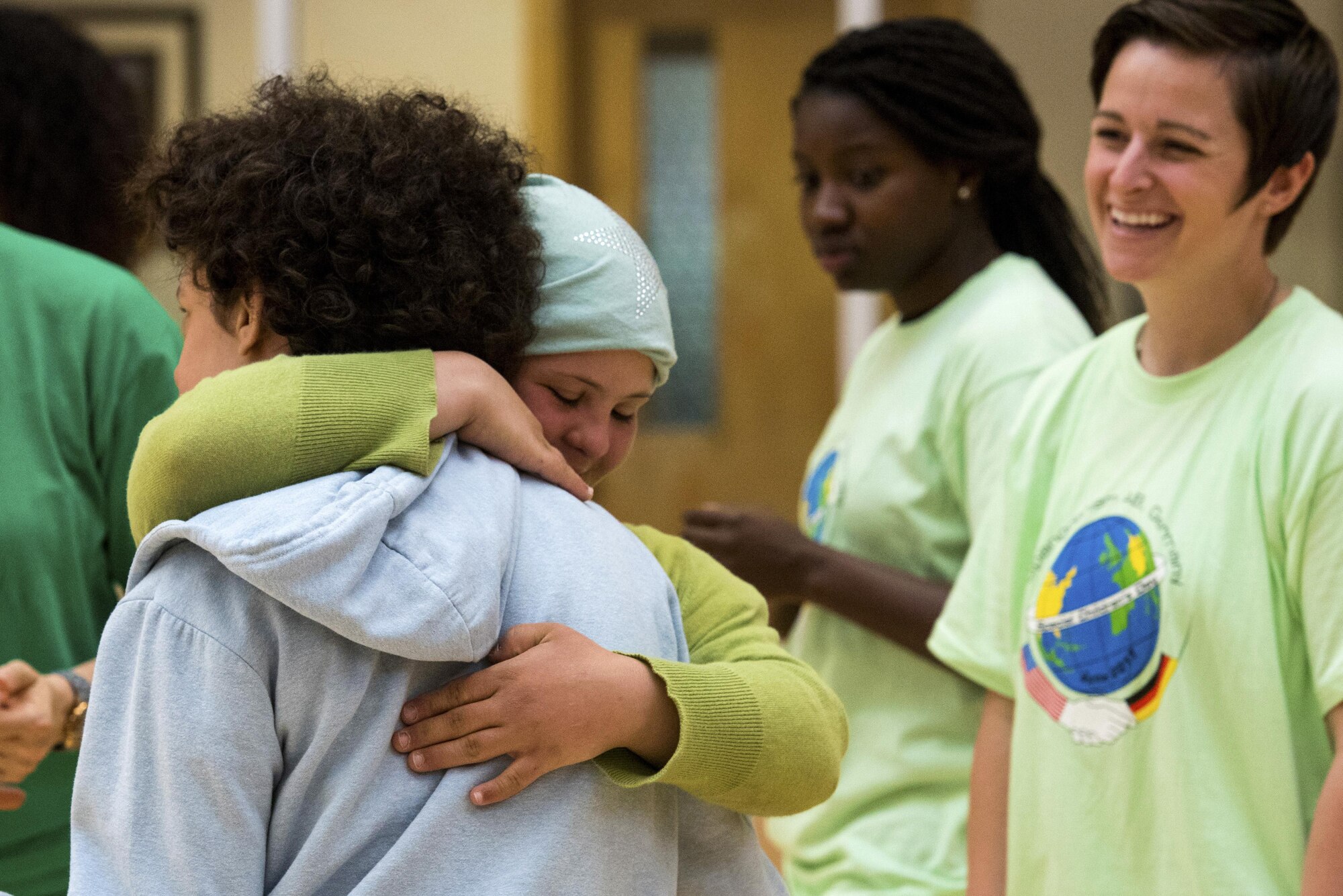 U.S. Air Force Staff Sgt. Jada Forney, right, 52nd Maintenance Squadron conventional maintenance crew chief, watches as Jennifer Erschfeld, center, student from Bitburg, hugs another participant during the St. Martins Special Children's Day at Spangdahlem Air Base, Germany, June 28, 2017. More than 80 Spangdahlem and Bitburg students participated in the event that gave children a chance to interact in different activities with one another. (U.S. Air Force photo by Senior Airman Preston Cherry)