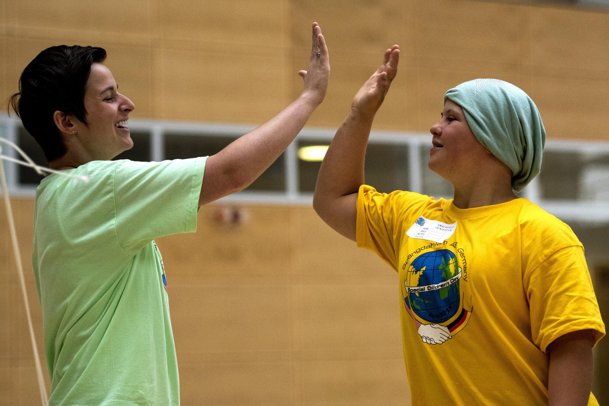 U.S. Air Force Staff Sgt. Jada Forney, left, 52nd Maintenance Squadron conventional maintenance crew chief, high fives Jennifer Erschfeld, right, student from Bitburg, during the St. Martins Special Children's Day at Spangdahlem Air Base, Germany, June 28, 2017. Each student from the event was paired up with a volunteer to participate in a variety of activities including basketball throw, hula-hooping, balance beam and bowling. (U.S. Air Force photo by Senior Airman Preston Cherry)