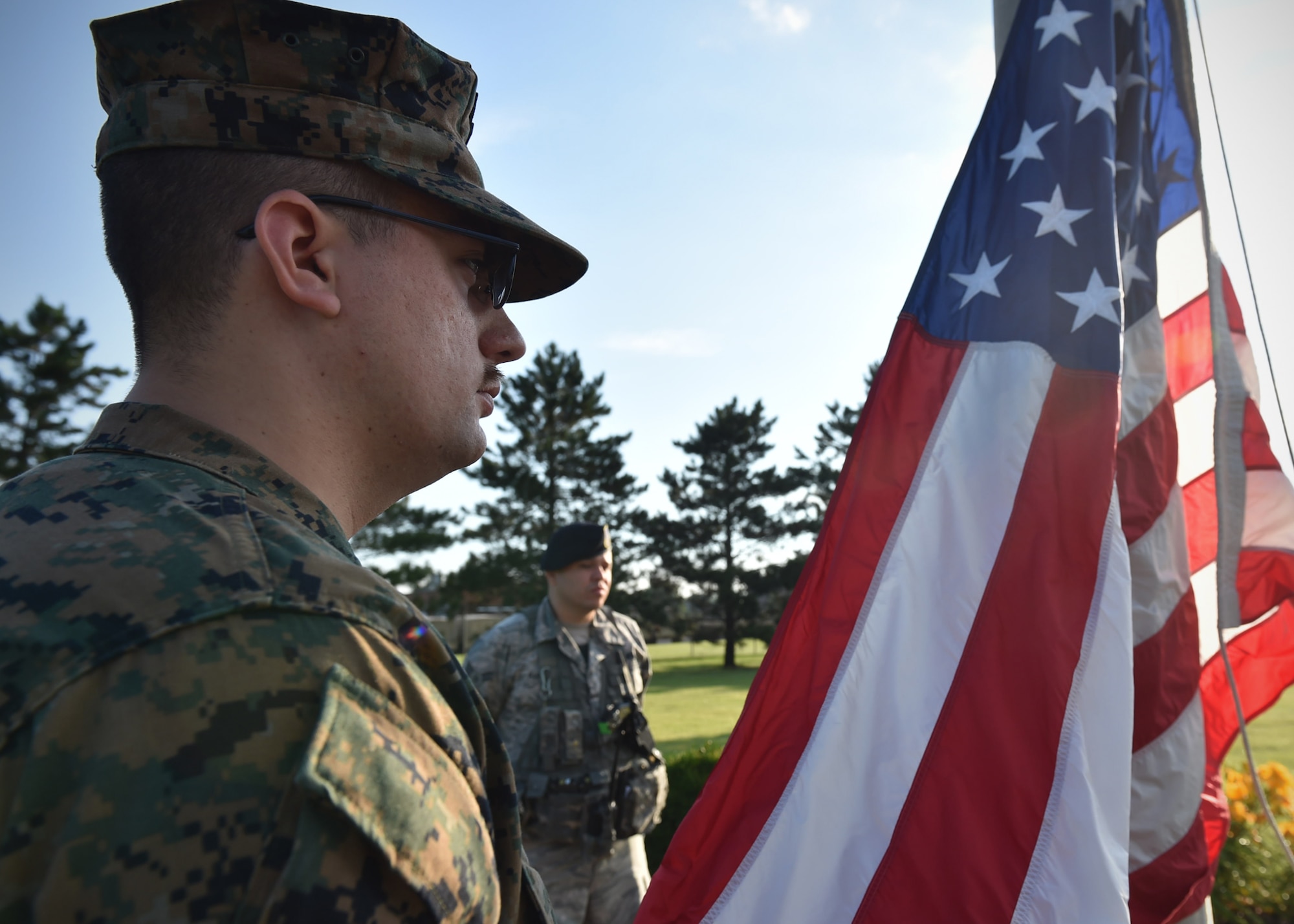 Petty Officer 2nd Class Phillip Nielson, Detachment 1 Communications Company corpsman, prepares to raise the American flag with Airman 1st Class Jose Martinez, 434th Security Forces Squadron patrolman at Grissom Air Reserve Base, Indiana, June 30, 2017. Celebrating its 75th anniversary, Grissom opened July 1, 1942, by the U.S. Navy and was known as Bunker Hill Naval Air Station. (U.S. Air Force photo/Staff Sgt. Katrina Heikkinen)