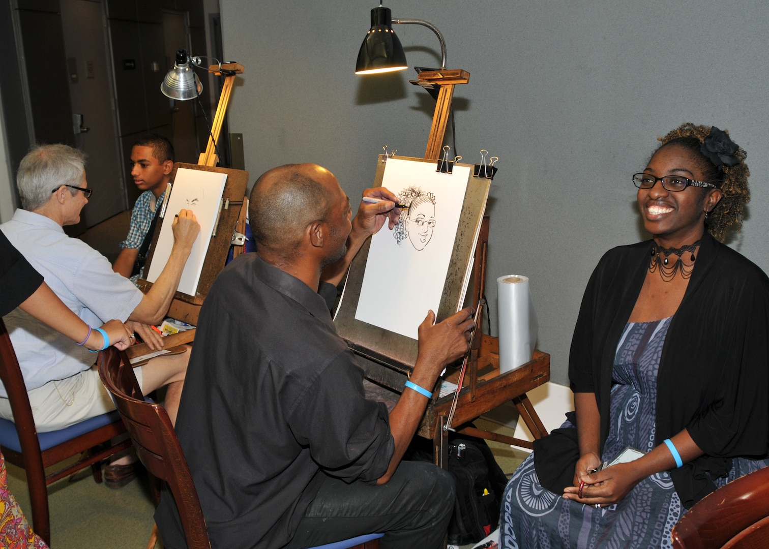 Employees and family members sit for free caricatures on Family Day at the McNamara Headquarters Complex.