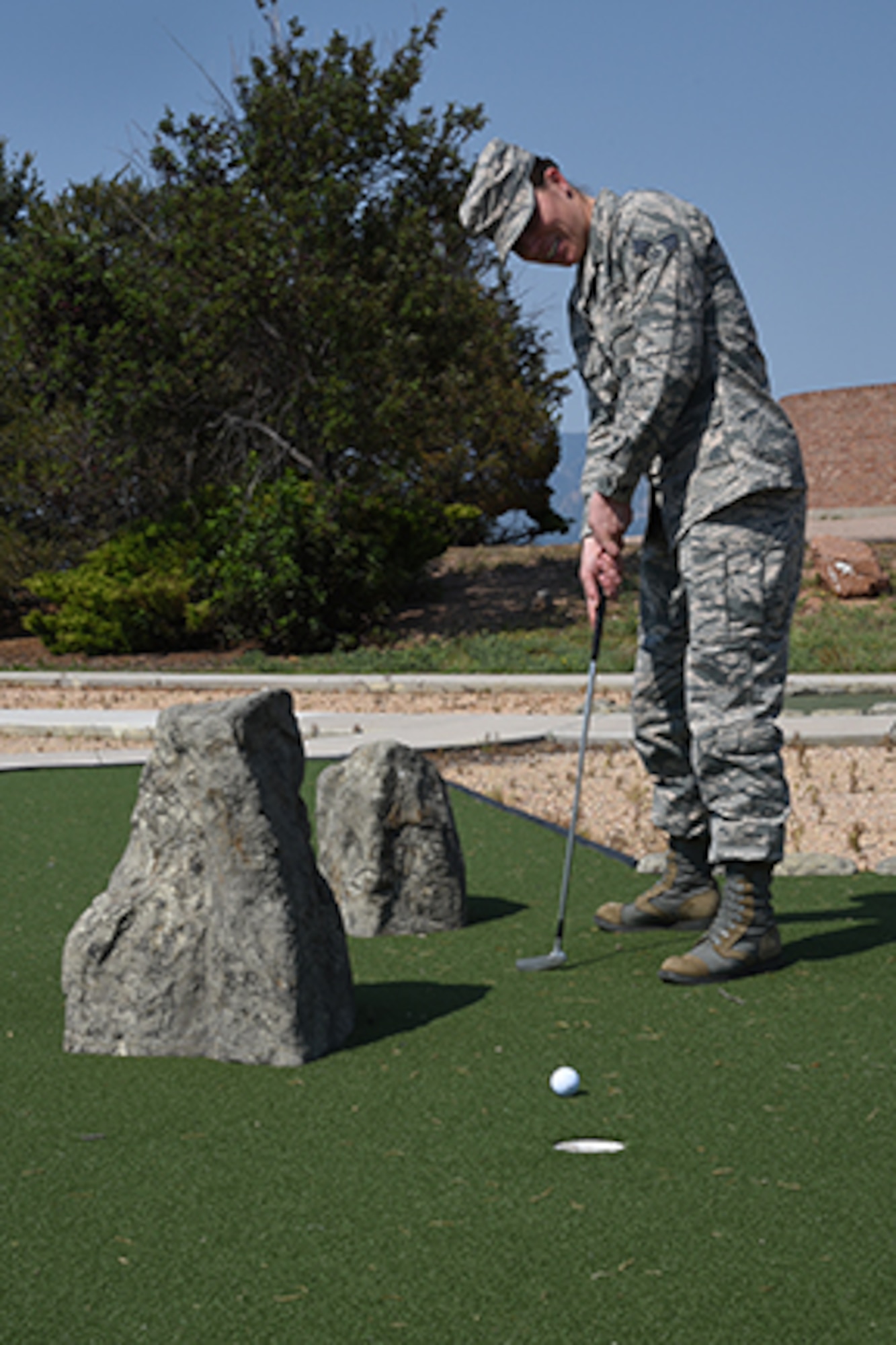 PETERSON AIR FORCE BASE, COLO. – Senior Airman Rose Gudex, 21st Space Wing Public Affairs photojournalist, holes out her putt on the third hole at Peak View Parks Putt-Putt golf course at Peterson Air Force Base, Colo., June 28, 2017. The nine-hole course offers outdoor recreation entertainment for Airmen stationed at Peterson AFB. (U.S. Air Force photo by Robb Lingley)  