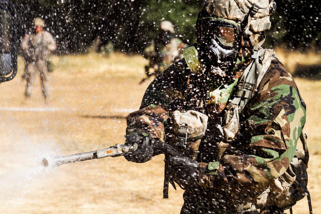 Army Sgt. Fernando Valadez sprays down a tactical vehicle during a decontamination mission that's part of Warrior Exercise at Fort Hunter Liggett, Calif., June 21, 2017. Valadez is assigned to the Army Reserve's 308th Chemical Company. Army photo by Spc. Derek Cummings