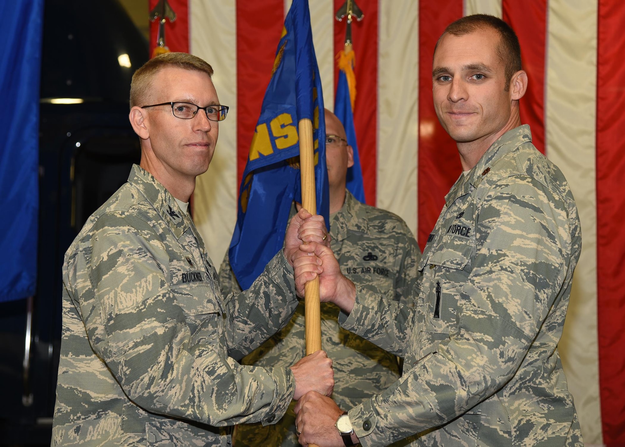 Col. Greg Buckner, 90th Maintenance Group Group commander, passes the guidon to Maj. Luke Stover, 90th Munitions Squadron commander, during the 90th MUNS change of command ceremony June 30, 2017 at the Maintenance Group High Bay on F.E. Warren Air Force Base, Wyo. The ceremony signified the transition of command from Maj. Kevin Barber to Stover. (U.S. Air Force photo by Glenn S. Robertson)