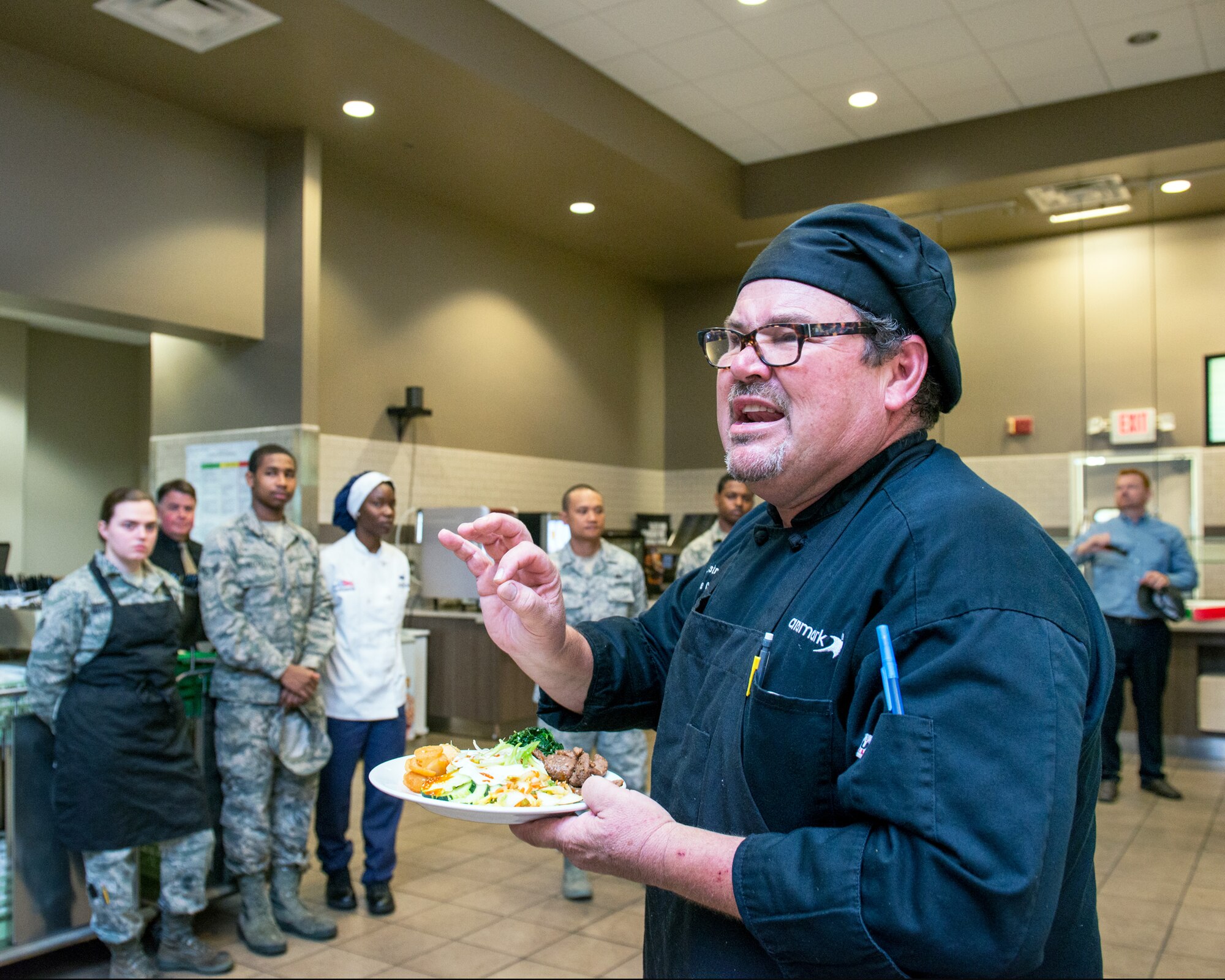 Maynard Oestreich, executive chef for Aramark explains his dish during the BIBIM Box tasting featuring Korean food at Sierra Inn Dining Facility, Travis Air Force Base, Calif., June 29, 2017. Oestreich a former U.S. Navy veteran and an award-winning chef from Napa Valley, Calif., took the head chef position so he could mentor young Airmen. (U.S. Air Force photo by Louis Briscese)